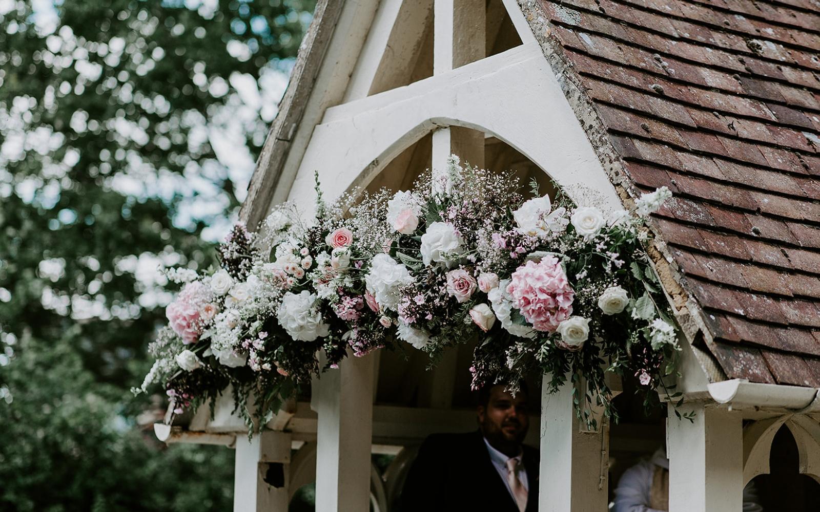 Real wedding Corky and Prince flowers florist stylist Gloucestershire Jenner's Barn Fairford Barn reception floral display over church entrance